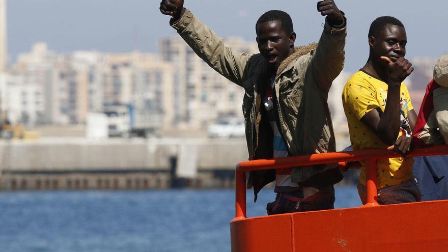 Un inmigrante levanta los brazos celebrando su llegada al puerto de Almería tras ser rescatados este jueves.