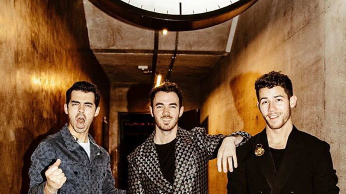 The Jonas Brothers posando juntos vestidos de traje