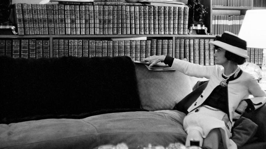 Retrato de Gabrielle Chanel en su sofá, mirando a su biblioteca.