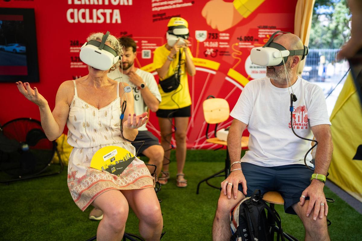 Dos aficionados usan la realidad virtual del Fan Park del Tour en Barcelona.