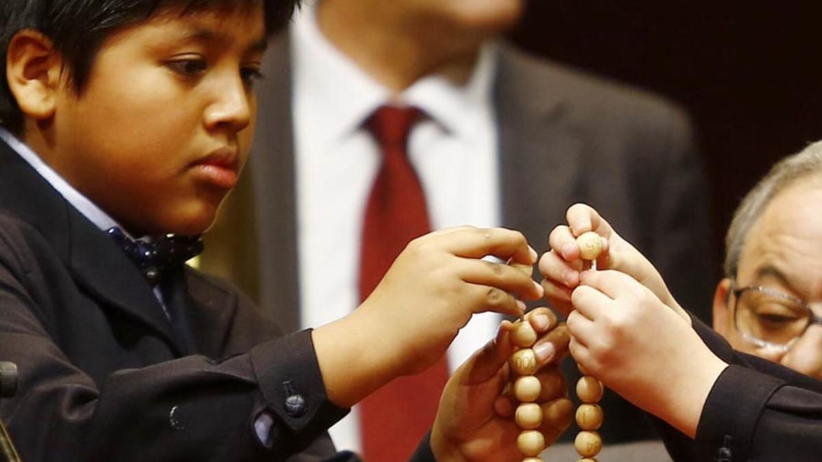 Dos niños ensartan las bolas de los números premiados de la Lotería de Navidad 2016.