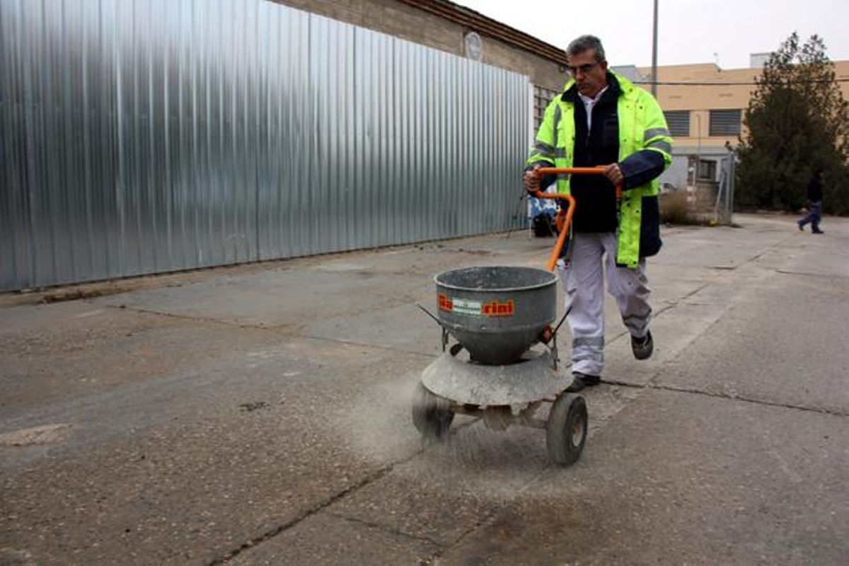 Un operari tira sal als carrers de Lleida.