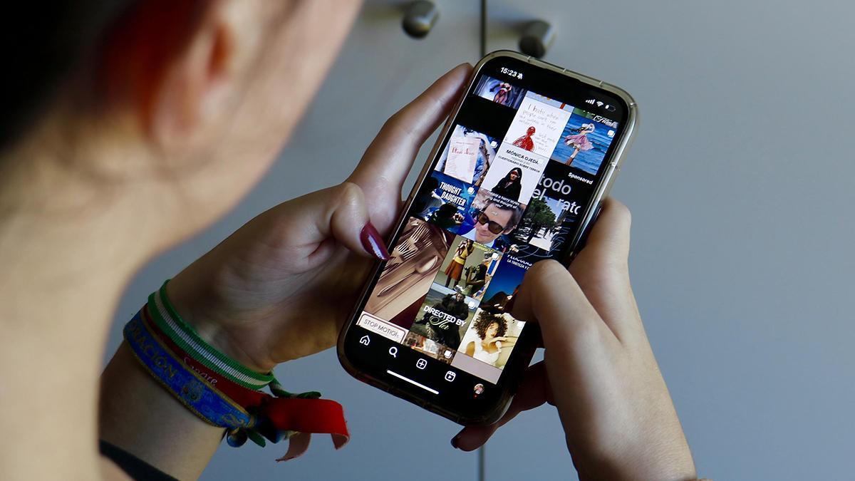 Una joven consulta sus redes sociales desde el móvil.