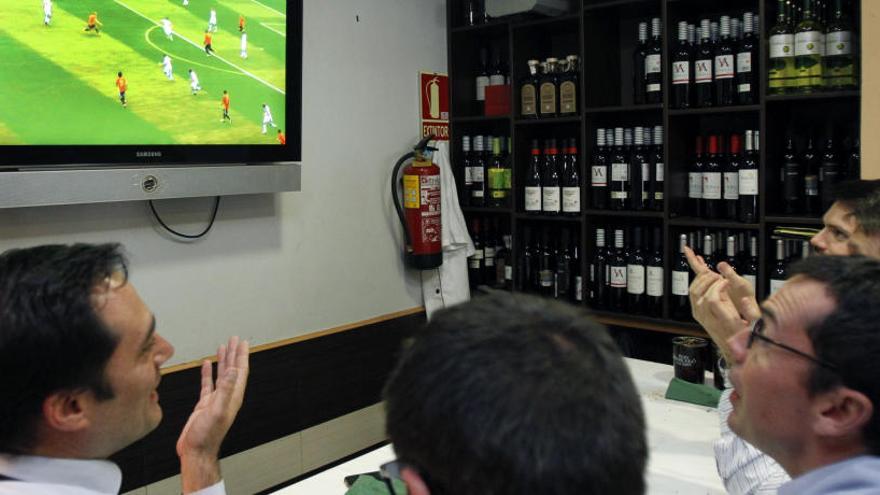 Varias personas siguen en un bar un partido de fútbol.