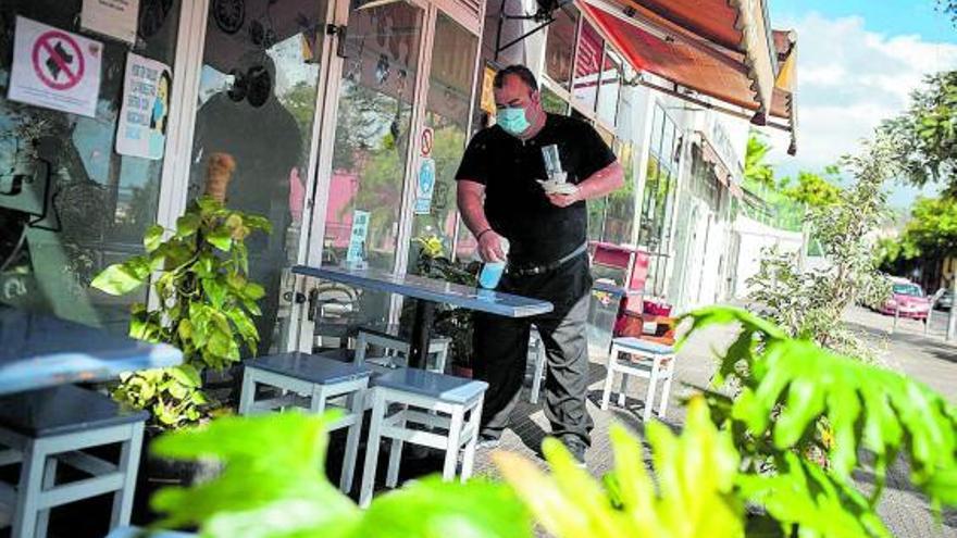 Un hostelero limpia una de las mesas de la terraza del establecimiento.