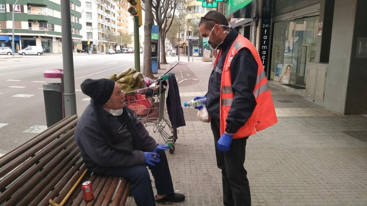 Un voluntario de Cruz Roja habla con un hombre que vive en la calle.