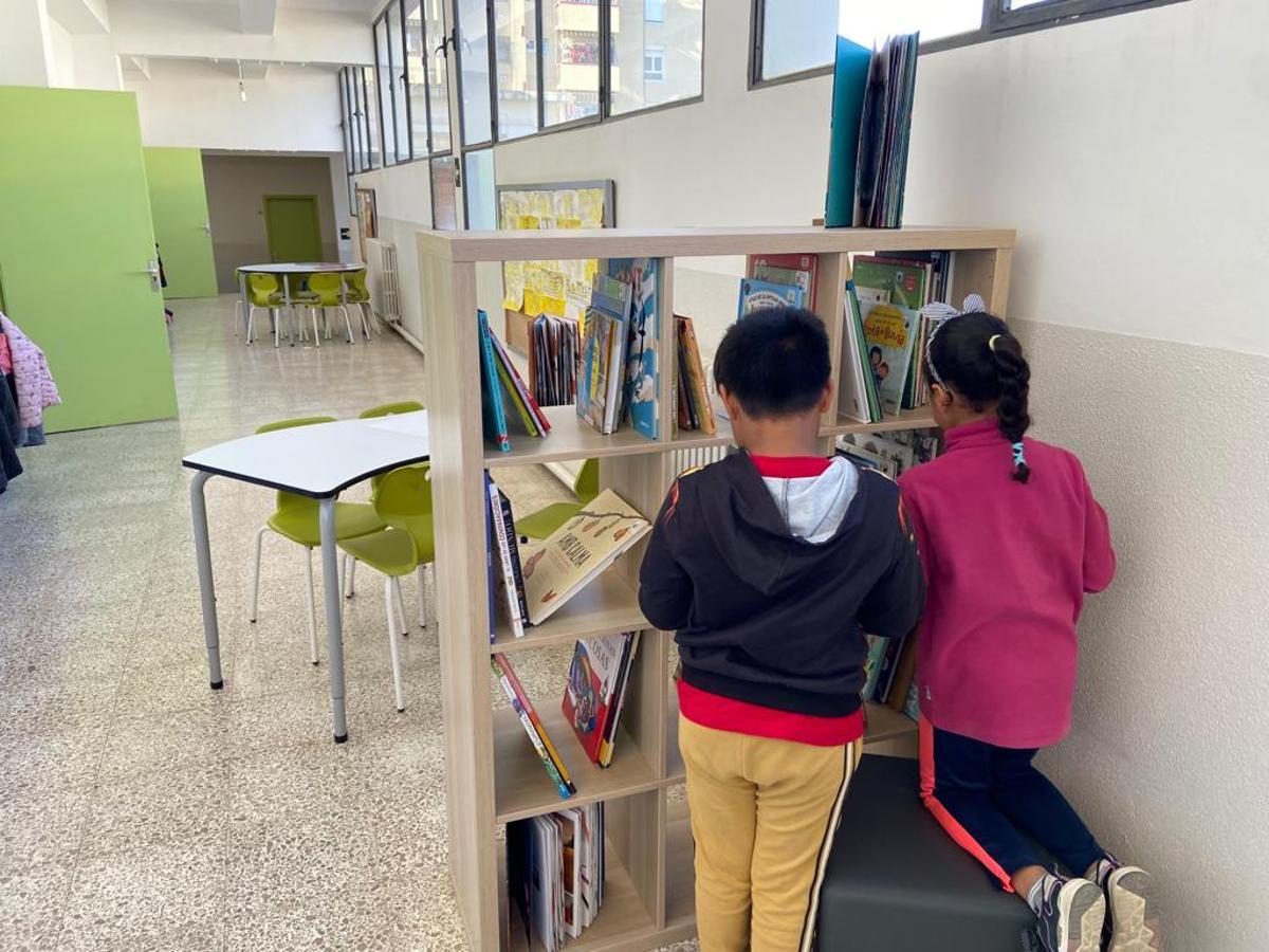 Dos alumnos de la escuela Espronceda, en Sabadell, consultan libros en un pasillo.