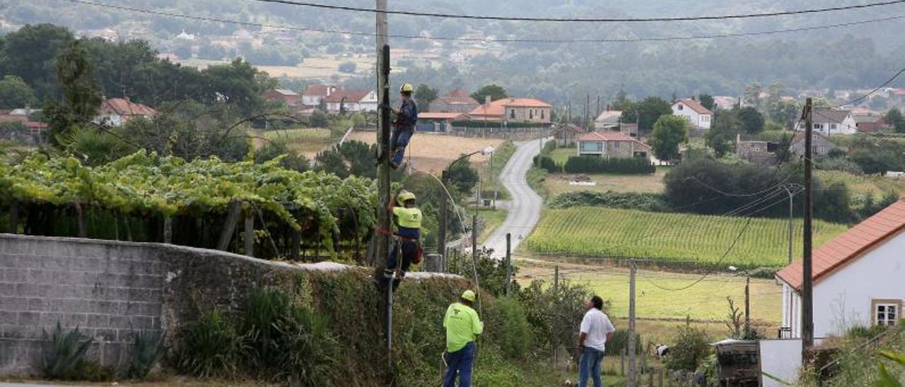 Operarios trabajando en la instalación aérea de fibra óptica en zonas del rural