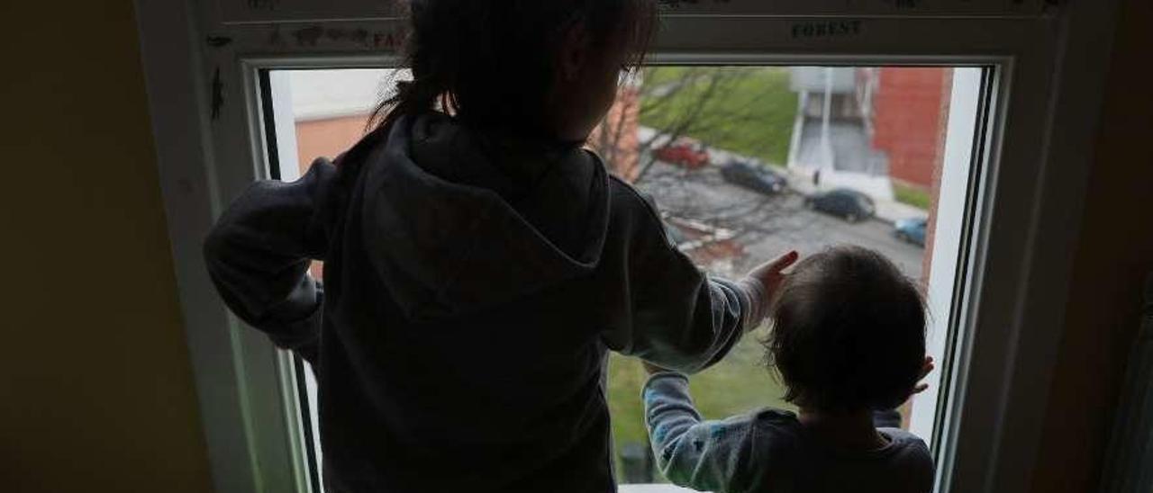 Dos niñas observan las calles avilesinas desde su domicilio.