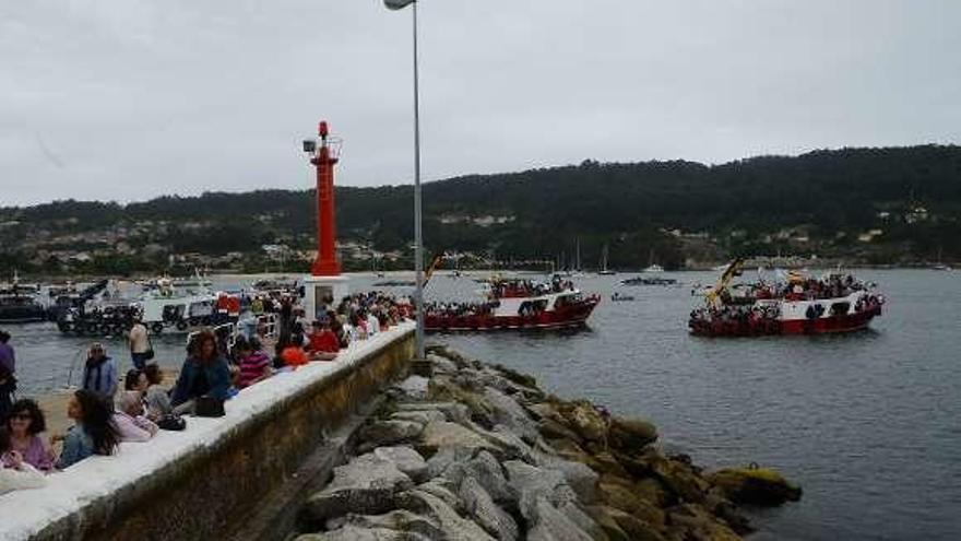 Decenas de personas observan desde el muelle la procesión. // G.N.