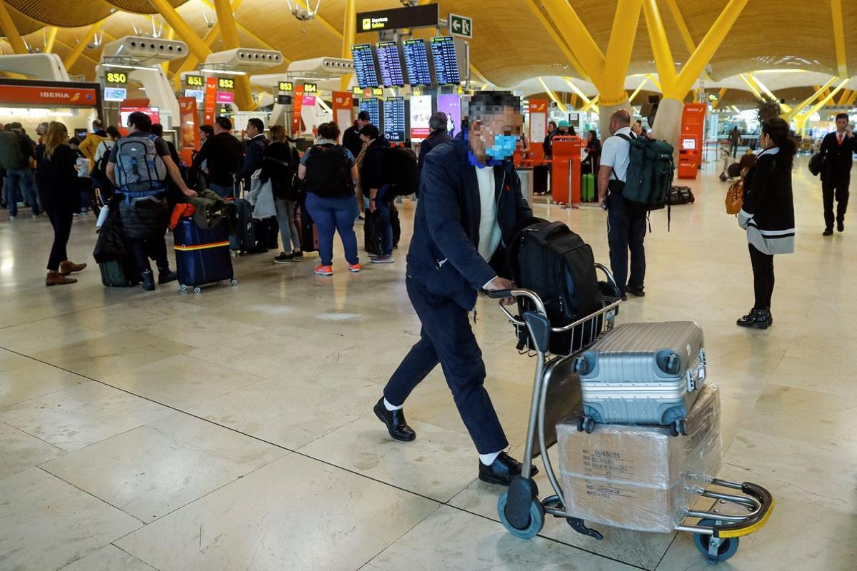 GRAF5811. MADRID, 12/03/2020.- Viajeros protegidos con mascarillas este jueves en el aeropuerto Madrid-Barajas Adolfo Suárez. La declaración del coronavirus como pandemia por parte de la OMS llevó este miércoles a extremar las medidas en América, donde EE.UU. suspendió por 30 días los viajes desde Europa. EFE/Emilio Naranjo