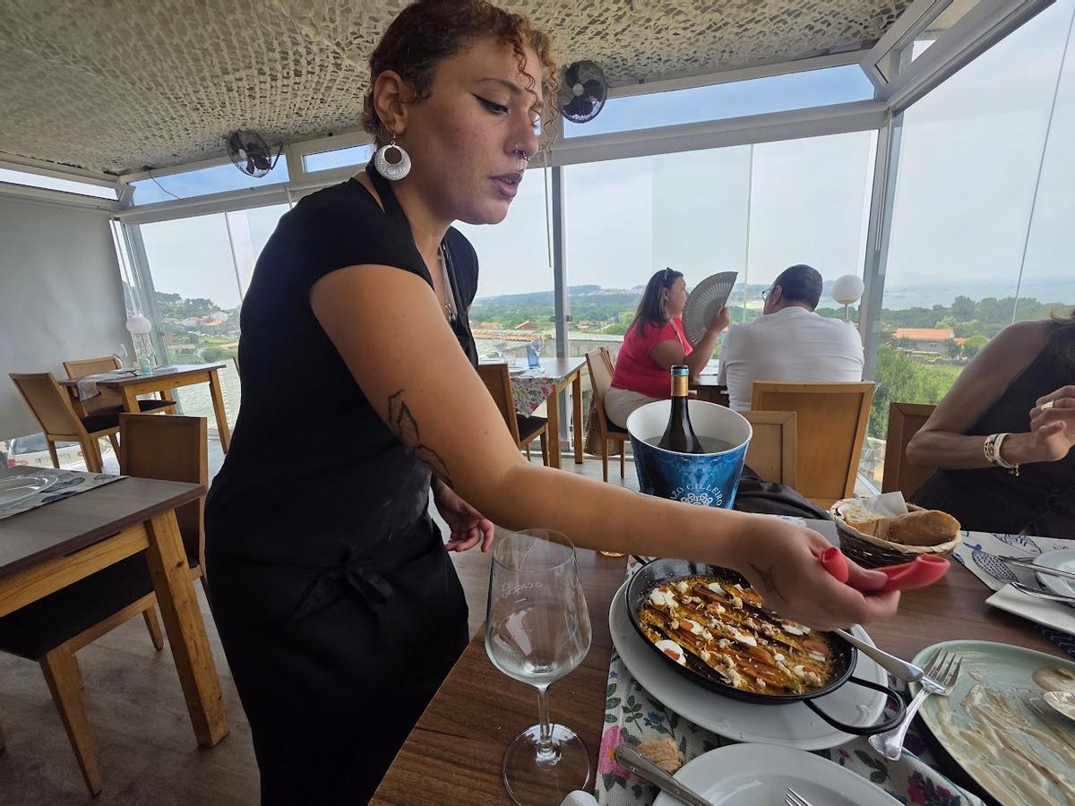 Una camarera sirve en mesa un plato a base de zanahorias caseras.