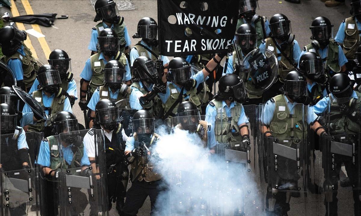 Violentos enfrentamientos en Hong Kong. La policía antidisturbios dispara gases lacrimógenos, avisando con un cartel, en los enfrentamientos con manifestantes. Decenas de miles de personas bloquearon arterias clave en una demostración de fuerza contra los planes del gobierno para permitir la extradición a China mediante una ley