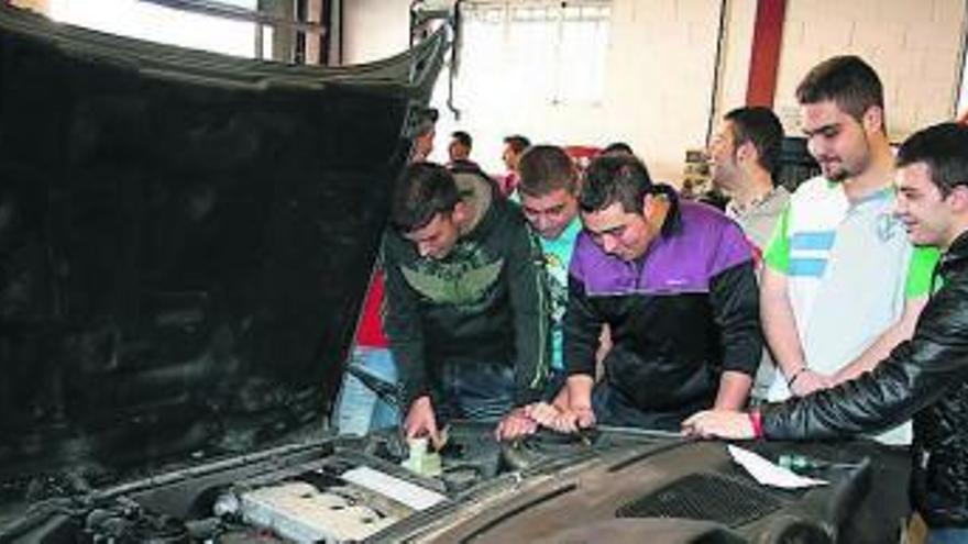 Alumnos en la exposición del ciclo de automoción, observando un motor y otros elementos mecánicos. | t. cascudo