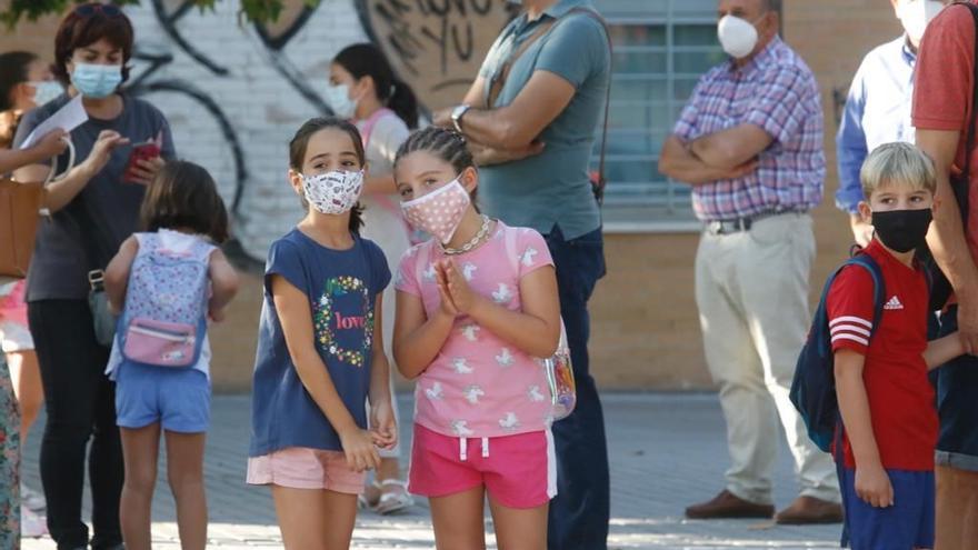 Alumnos con mascarillas esperando para entrar al colegio.