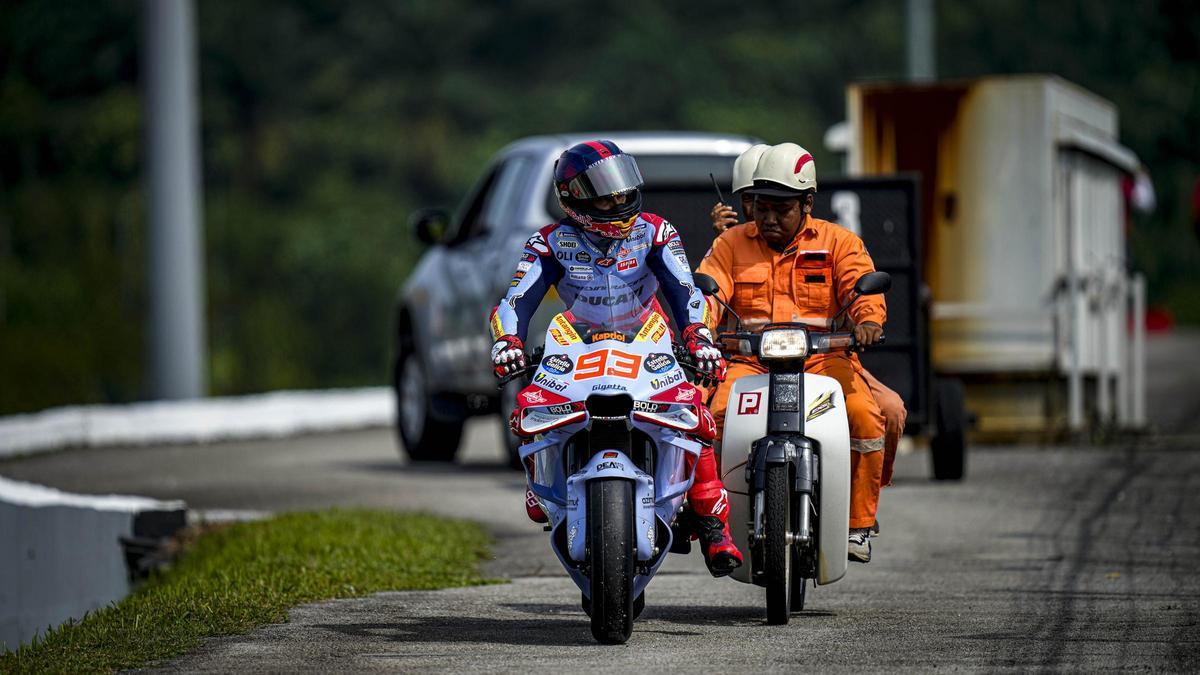 Un comisario de pista de Sepang ayuda a Marc Márquez tras pararse su Ducati, hoy, en Sepang.
