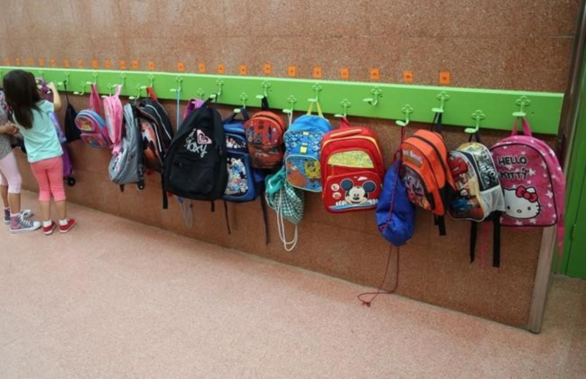 Una niña coloca su mochila en los colgadores de su clase de infantil en un colegio de Badalona.