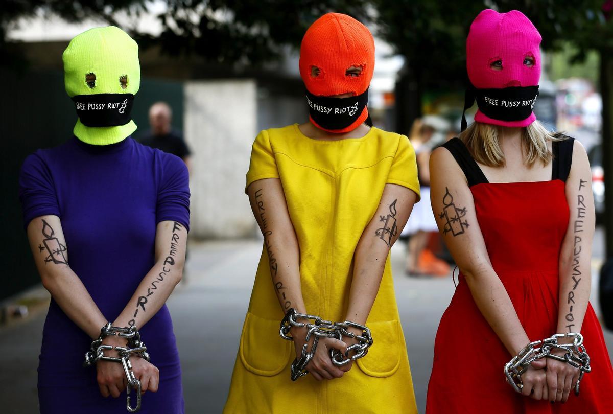  Un grupo de simpatizantes de las &quot;Pussy Riot&quot; con pasamontañas fluorescentes, pañuelos en la boca y las manos encadenadas.