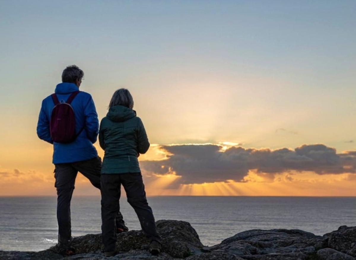 Dous vistantes gozando dunha posta de sol en Costa da Morte.