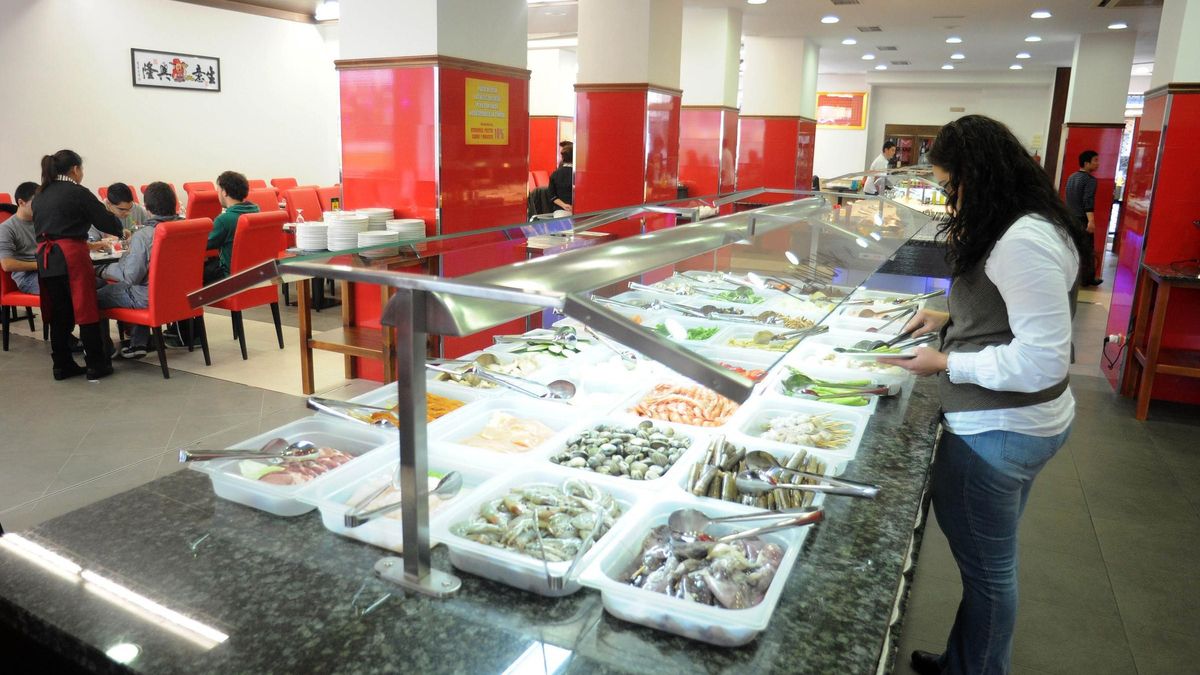 Una mujer se sirve comida en un buffet libre.