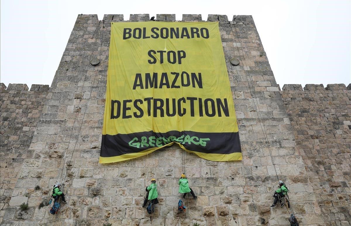 Activistas de Greenpeace colocan una gran pancarta con motivo de la vsita del presidente de Brasil, Jair Bolsonaro a Jerusalen. 