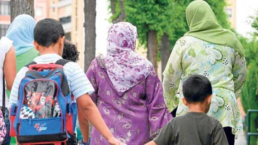 Dos niños van al colegio acompañados por sus madres.