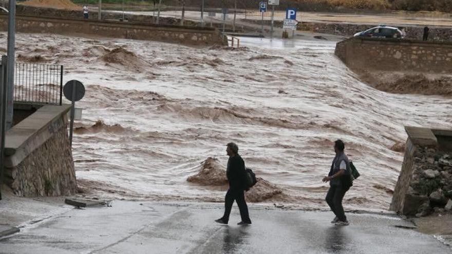 Una pareja pasa junto a una desbordada rambla del Guadalentín durante las inundaciones de 2012.