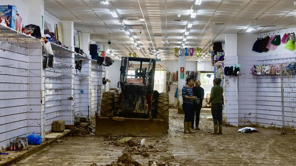 Personal de un comercio devastado por las inundaciones y el barro en Alfafar.