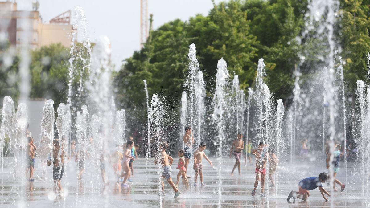 Gente refrescándose en València bajo aviso rojo en la fuente del Parc Central.