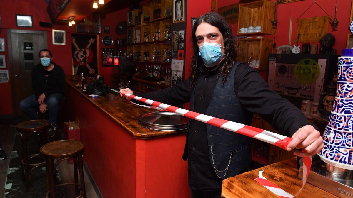 Un hostelero de A Franxa, en A Coruña, muestra una cinta con la que precinta la barra de su local.