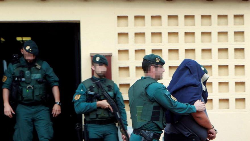 Agentes de la Guardia Civil trasladan a un detenido durante uno de los registros realizados en una vivienda de la calle Espartel en la barriada del rinconcillo en Algeciras (Cádiz)