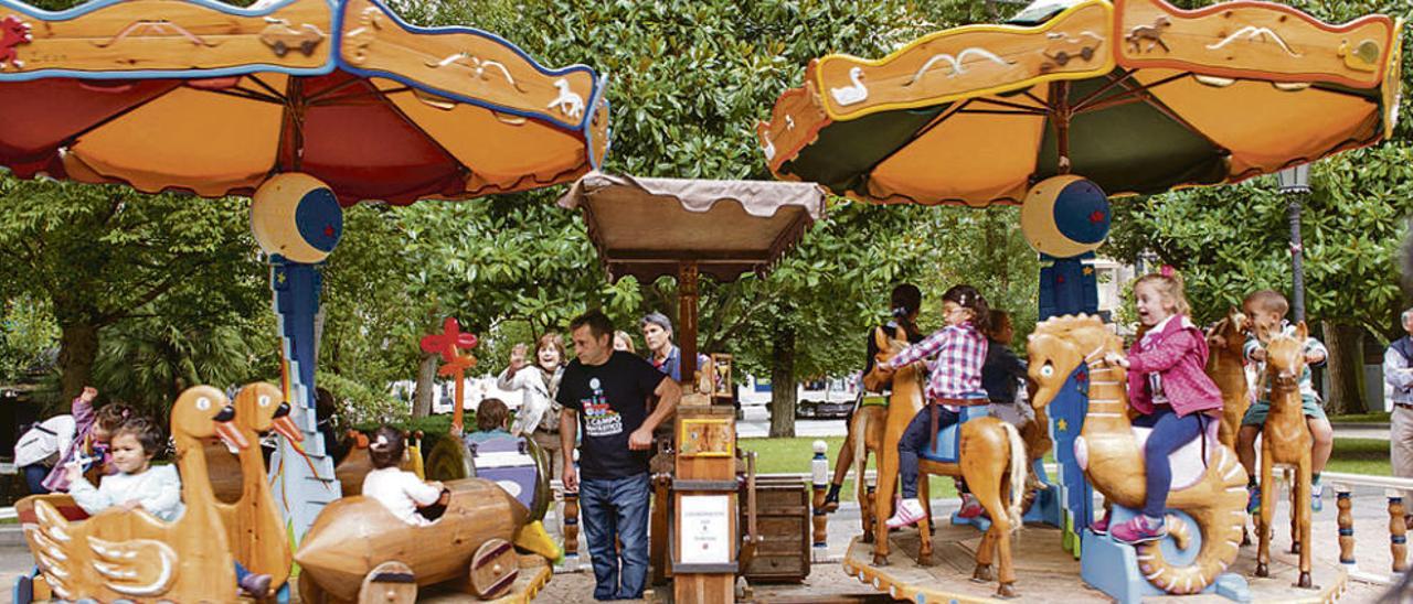 Niños en los dos carruseles de manivela instalados en el Campo San Francisco.