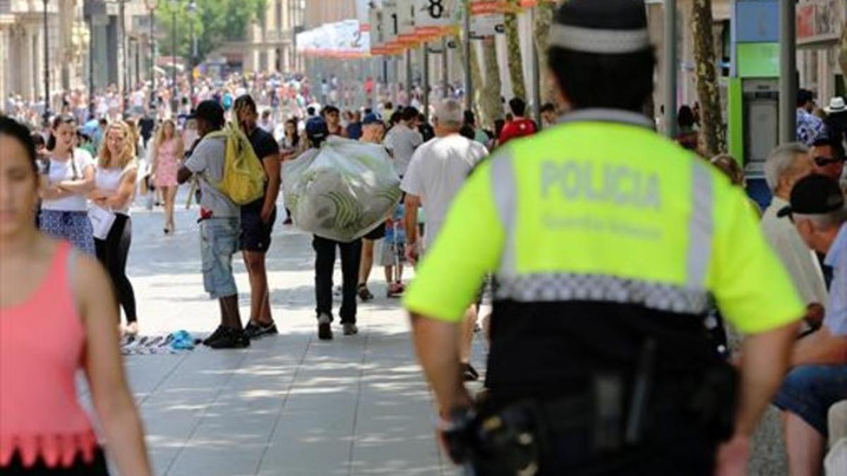 Un guardia urbano se acerca a unos manteros en Portal de l'Àngel, ayer.