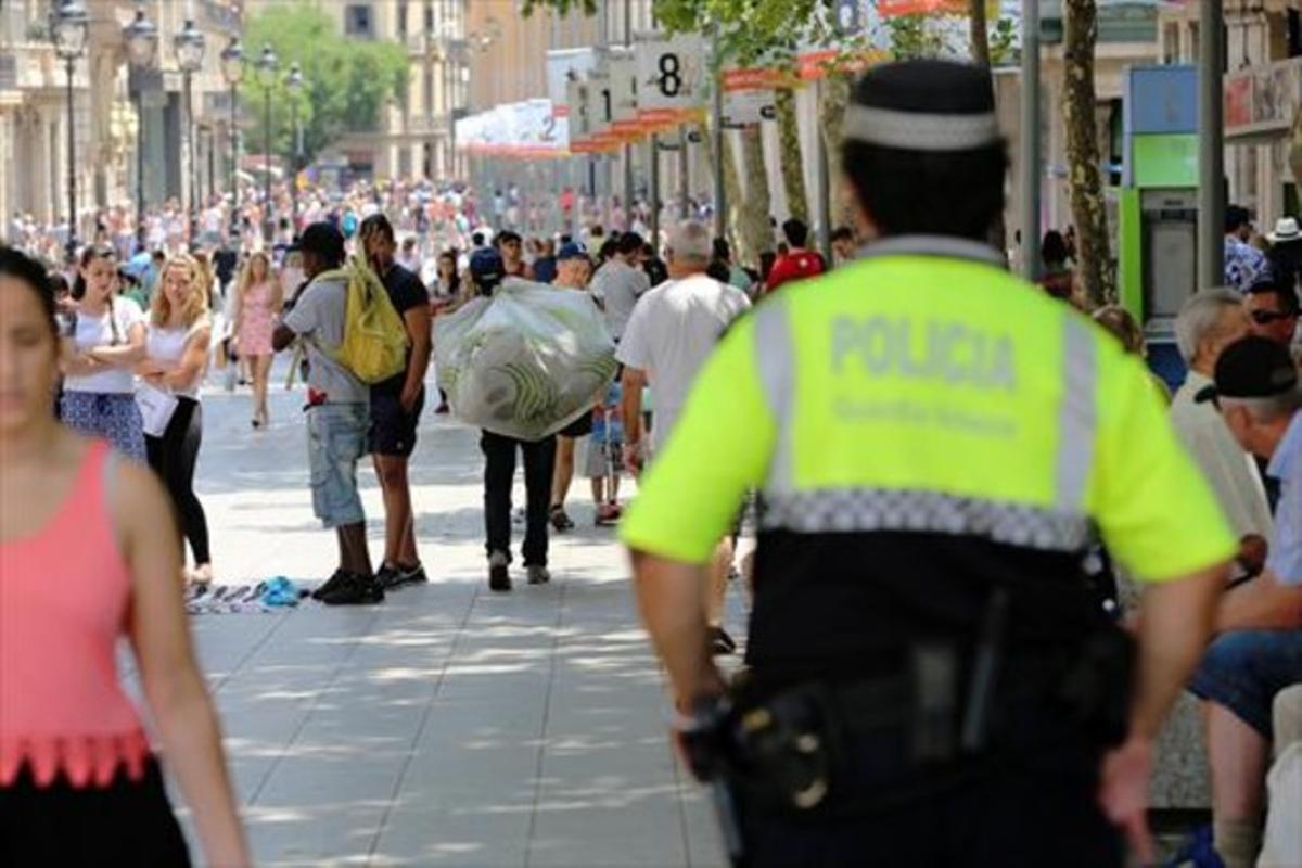 Un guàrdia urbà s’acosta a uns manters al Portalde l’Àngel, ahir.