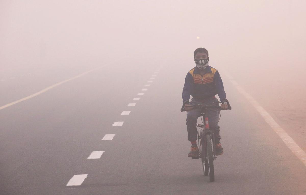 Un niño con mascarilla avanza en bicicleta por Nueva Delhi, la India.