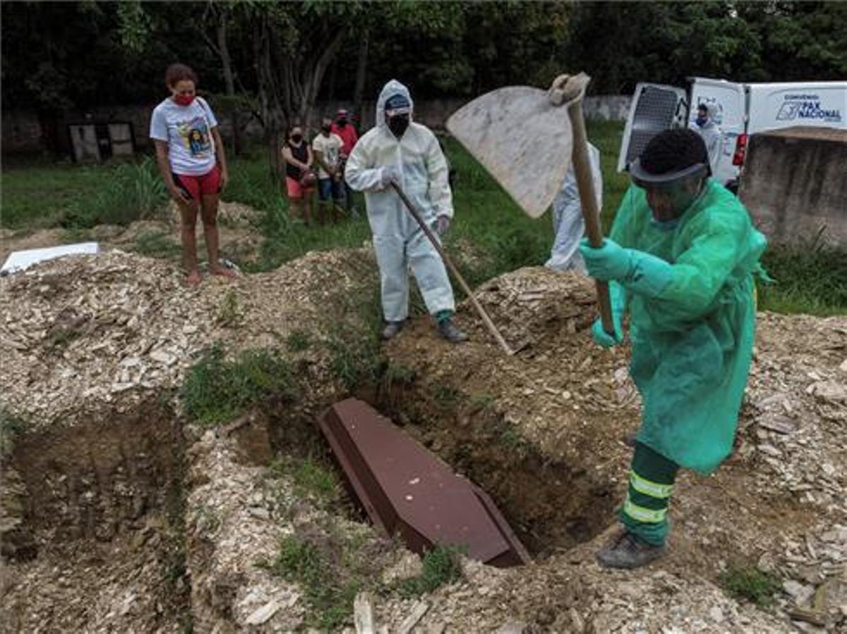 Familiares observan el entierro de un joven de 28 años muerto por coronavirus, en el cementerio Despraiado en Cuiabá, capital de Mato Grosso (Brasil). 