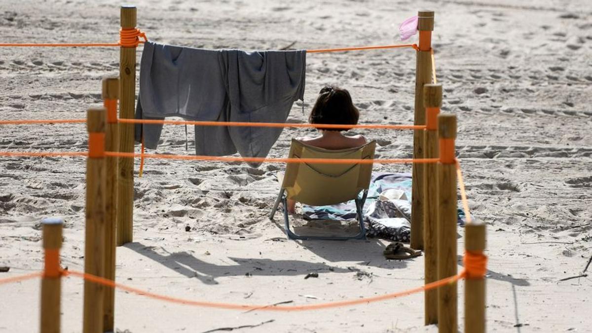 Una mujer sentada en la playa.