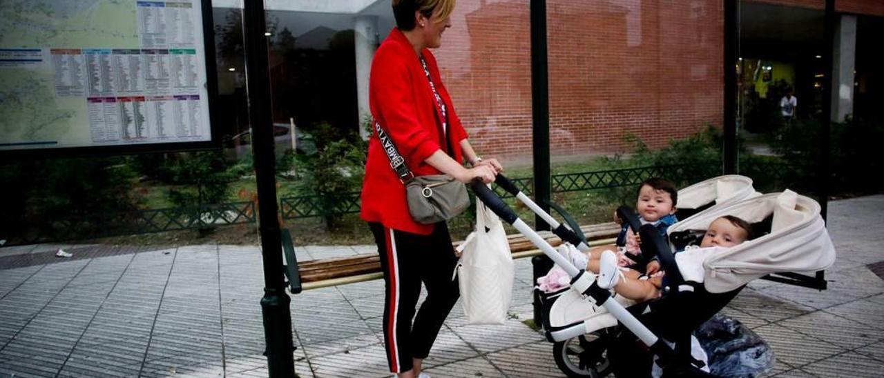 Belén García, con sus dos hijas, en la parada de autobús de la calle Llaviada, en La Corredoria.