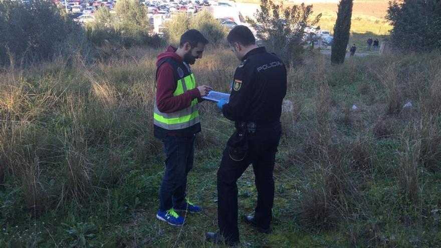 Dos agentes toman nota del hallazgo de los huesos en el área descampada próxima al hospital de Alzira.