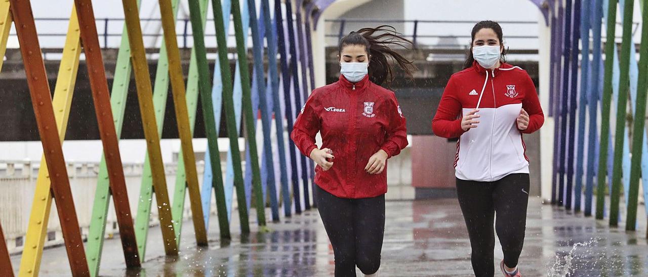 Alba Barreiro y Alicia Currás, en el puente de San Sebastián, durante su recorrido bajo la lluvia.