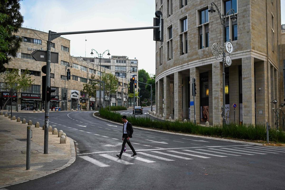Un hombre cruza un paso de peatones en una calle vacía.