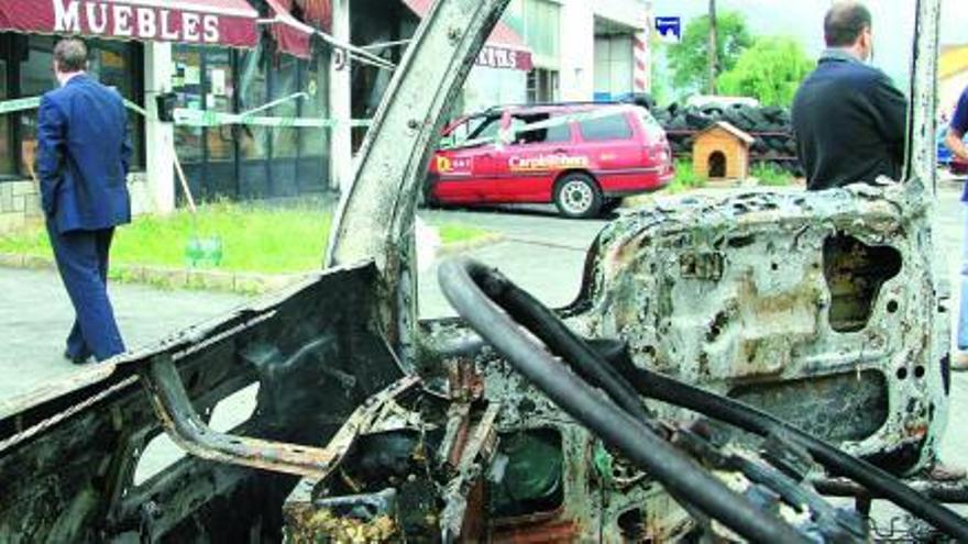 Uno de los vehículos afectados, con la carpintería donde se produjo el incendio al fondo de la imagen.