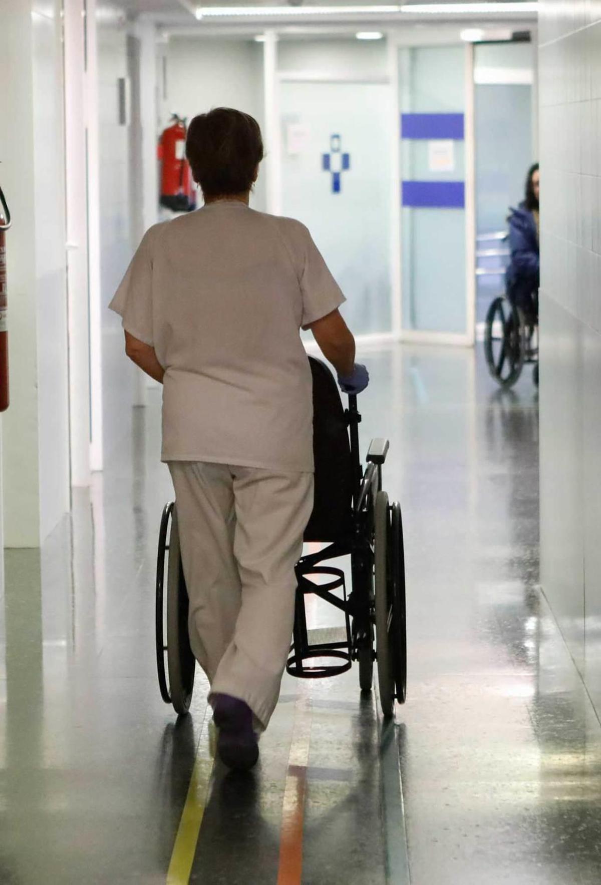 Una trabajadora de Cabueñes, con una silla de ruedas por un pasillo del complejo hospitalario.