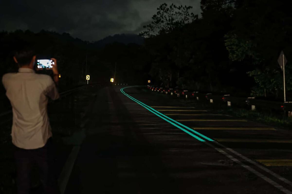 Un hombre fotografía la carretera con pintura fluorescente.