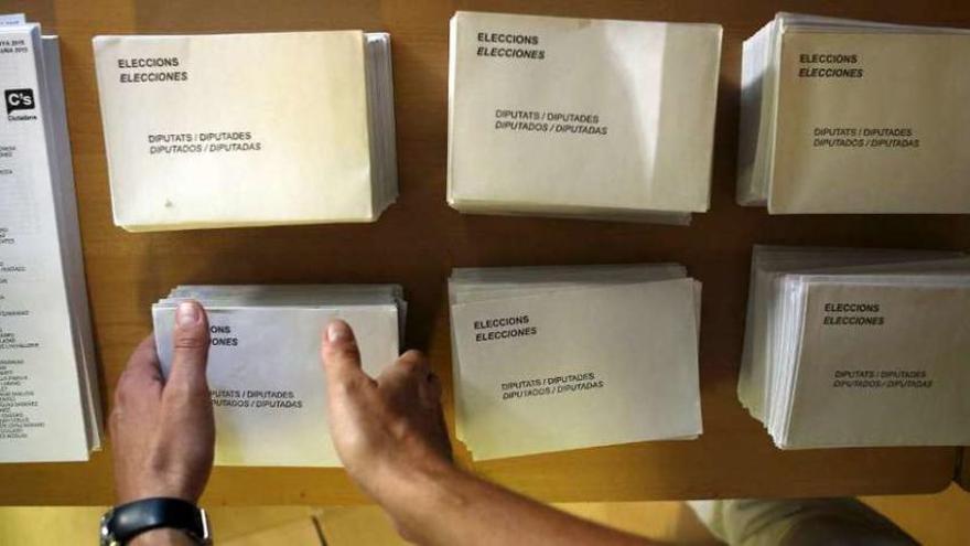 Un hombre coloca papeletas en una m esa electoral de Cataluña.