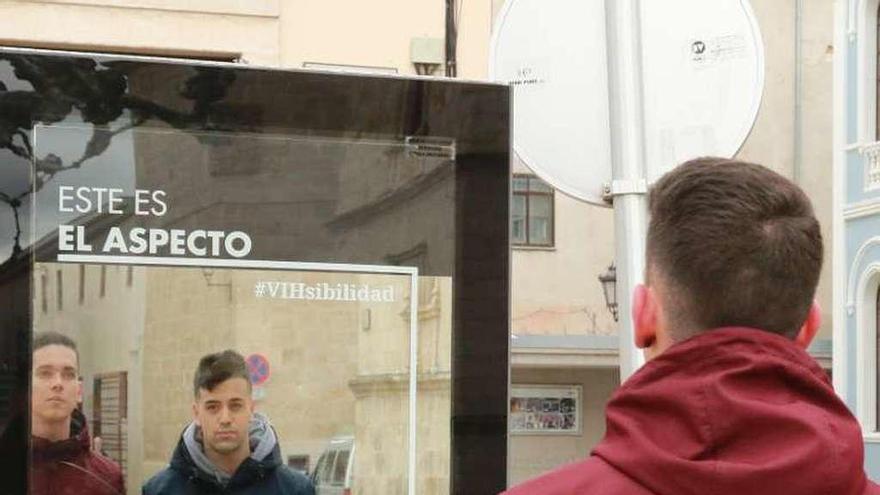 A la izquierda, varios jóvenes observan la publicidad instalada en la plaza de Viriato y a la derecha, otro zamorano lee el otro lado del mupi .