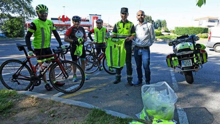 Agentes de la Guardia Civil de Tráfico repartiendo estos chalecos reflectantes a ciclistas ayer en O Vinquiño. // Gustavo Santos