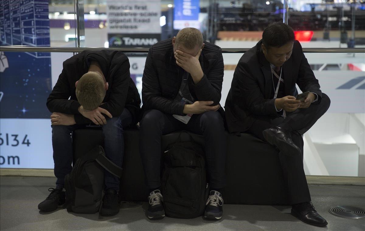 Tres visitantes del Mobile World Congress muestran su fatiga en el primer día del evento.