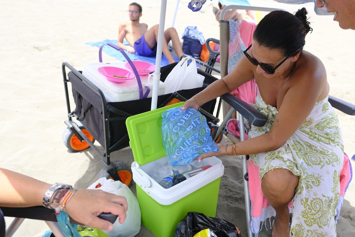 Jennifer Santana enfría las bebidas con hielo en la playa de El Pajar.