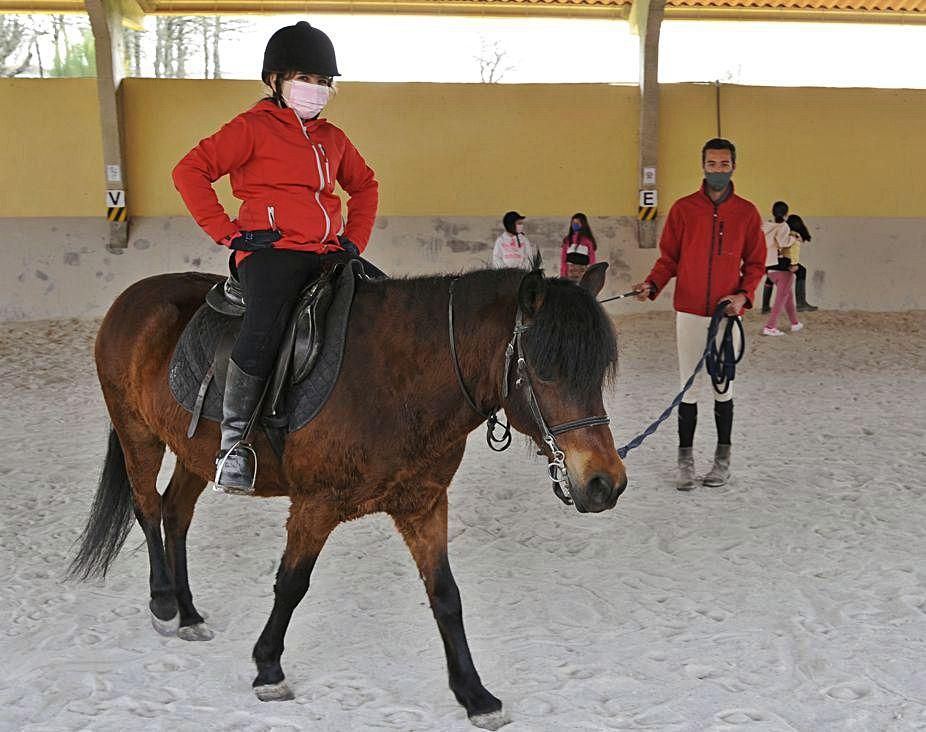 Una niña practica equitación con un monitor.